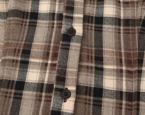 Détail macro de la chemise à carreaux avec texture tissée brune et boutons marron foncé