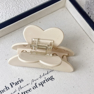 Detail of a beige flower claw clip with a transparent metal spring on a tray