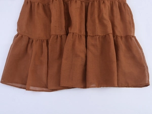 Close-up detail of tiered brown skirt hem with textured fabric and ruffle design