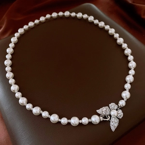 Détail d'un collier de perles avec fermoir papillon en zircon sur cuir et soie