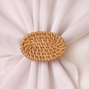 Detail of handmade woven rattan napkin ring in oval shape on white cloth napkin