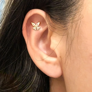 Close-up of golden butterfly cartilage stud earring with sparkling zircon on ear