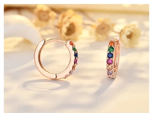 Detail view of rose gold hoop earrings with multi-colored cubic zirconia and floral background