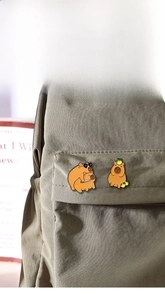 Gros plan d'épingles en émail Capybara mignonnes sur un sac à dos en toile verte