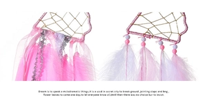 Detail of pink heart dreamcatcher with feathers, colorful beads, and satin ribbons