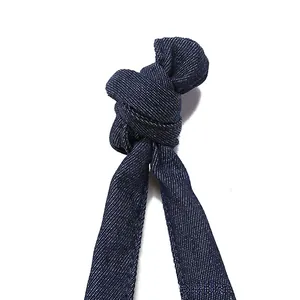 Macro view of dark blue denim strap with white twill texture and knotted fabric detail