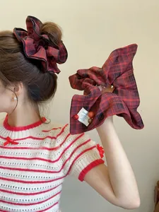 Detail of red and black plaid scrunchie featuring a white label with Happy text