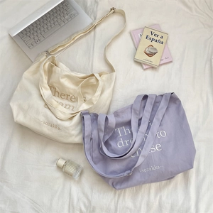 Close-up of cream and lilac canvas tote bags with adjustable straps on soft fabric