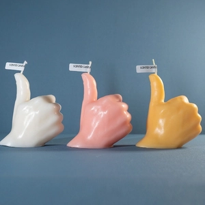 Candele profumate a forma di pollice in su in bianco, rosa e giallo su sfondo blu