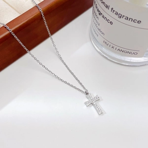 Collier croix style hip-hop en argent avec zircons sur un fond blanc au décor épuré