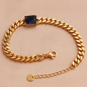 Detailed macro view of gold-plated chain bracelet with blue rectangular zircon and lobster clasp