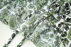 Macro shot of green floral print on textured seersucker fabric with ruffle tie detail