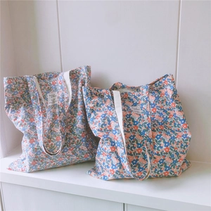Detail view of two floral cotton canvas tote bags with fresh red and blue flower patterns