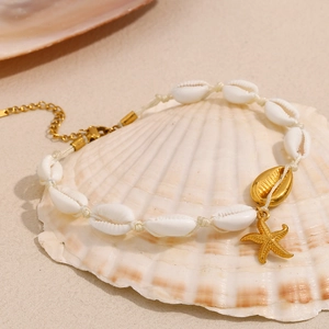 Détail de la chevillère étoile de mer et coquillage dorée 18K sur un décor de plage