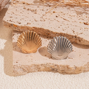 Detailed close-up of shell-shaped gold and silver ear cuffs with radial texture on stone
