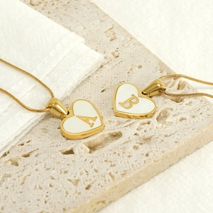 Detailed macro of gold heart pendants with letters A and B on a stone surface