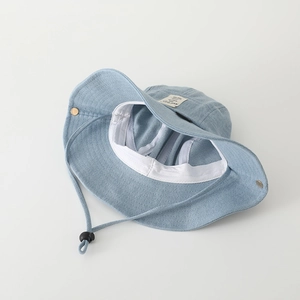 Detail of light blue denim bucket hat with adjustable chin strap and metal snap buttons
