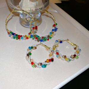 Detailed shot of two pairs of gold circular earrings featuring colorful crystal beads and pearls