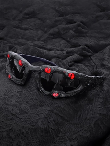 Detail of gothic black sunglasses featuring realistic red eyeballs and textured frames