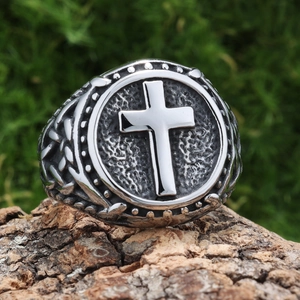Macro detail of retro stainless steel signet ring with cross totem on rustic wood bark