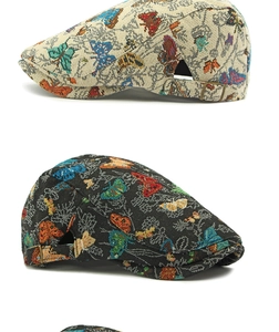 Detail view of jacquard flat cap showing colorful butterfly embroidery and metal side buckle