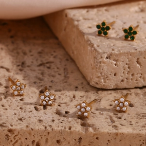 Détail macro de boucles d'oreilles fleuries plaquées or 18 carats avec émeraude et perle
