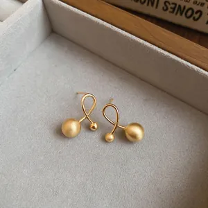 Gold plated twist ribbon stud earrings with matte and polished beads on velvet display