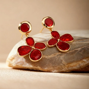 Vintage red flower stud earrings with gold plating on a natural stone background
