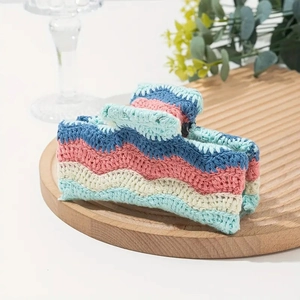 Close-up of a handmade crochet hair claw clip with colorful wavy knitted patterns