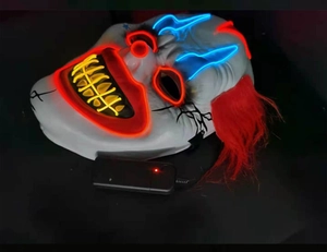 Macro detail of LED glowing clown mask with red hair and integrated power controller