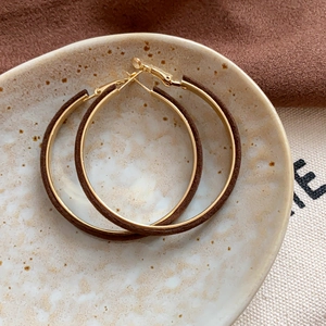 Macro detail of vintage flocked gold hoop earrings on a textured ceramic surface
