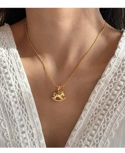 Detailed view of a gold rocking horse pendant necklace worn on a white lace top