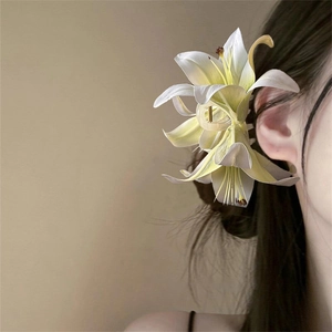 Close-up of a 3D white lily hair claw clip securing an elegant French-style updo