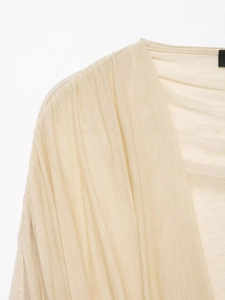 Close-up of beige knit fabric texture with pleated design and V-neckline detail