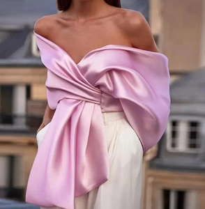 Détail d'un haut rose satiné épaules dénudées avec un grand nœud et texture plissée