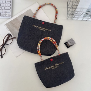 Detail of blue denim handbags with embroidered letters and colorful woven handles