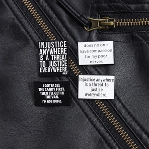 Detail of inspirational black and white enamel pins pinned on a black leather jacket