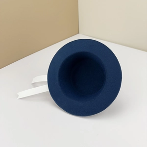 Close-up of a 20cm navy blue felt doll hat with white grosgrain ribbons and school style