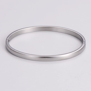 Detail view of the silver metal bangle with a brushed matte finish and side clasp mechanism