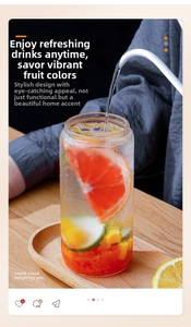 Action shot pouring water into a clear 16oz glass cup with bamboo lid and citrus fruit slices