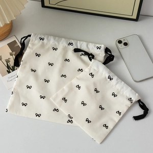 Detail view of two cream drawstring bags with black bow patterns for storage