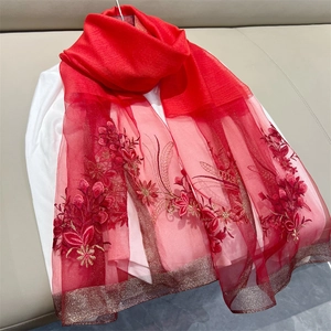 Detailed close-up of red embroidered floral scarf with elegant gold metallic trim edges