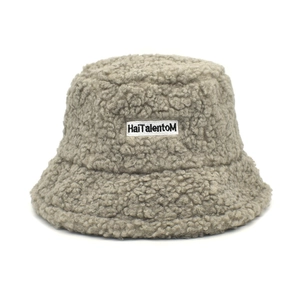 Détail d'un bob en polaire sherpa grise avec un écusson brodé de texte noir élégant