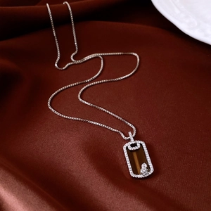 Détail macro du collier chaîne en argent avec pendentif rectangulaire sur soie