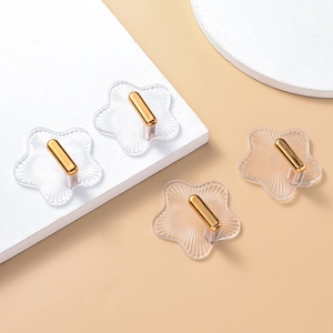 Detailansicht von vier sternförmigen transparenten Klebehaken mit eleganten Goldmetallspitzen