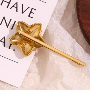 Detailed close-up of a 18K gold-plated stainless steel star hair clip on a minimalist surface
