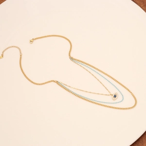 Layered gold evil eye necklace with blue seed beads and stainless steel pendant detail