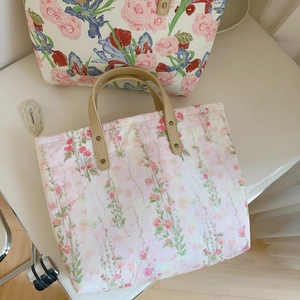 Detail of floral canvas tote bags with brown leather handles and sturdy metal rivets