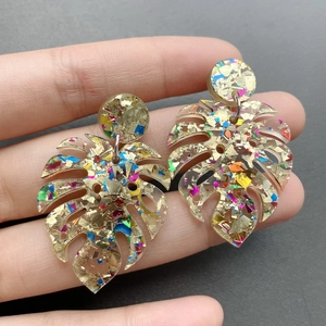 Detailed view of monstera leaf earrings with colorful sequins and gold foil flakes