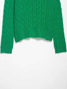Detail of chunky cable knit hem and cuffs on a vibrant green V-neck sweater